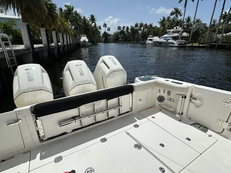Slide: The Image of 2022 Boston Whaler 405 Conquest boat with triple engines docked by a scenic waterway. - 16