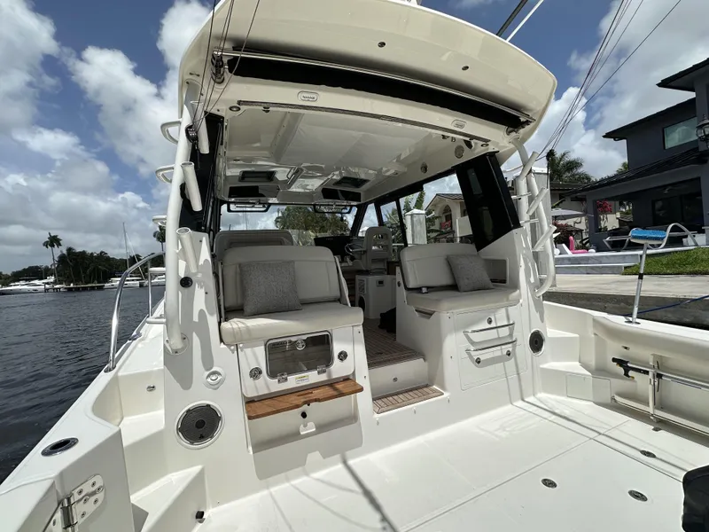 Slide: The Image of 2022 Boston Whaler 405 Conquest boat interior with seating, docked by waterfront homes. - 18