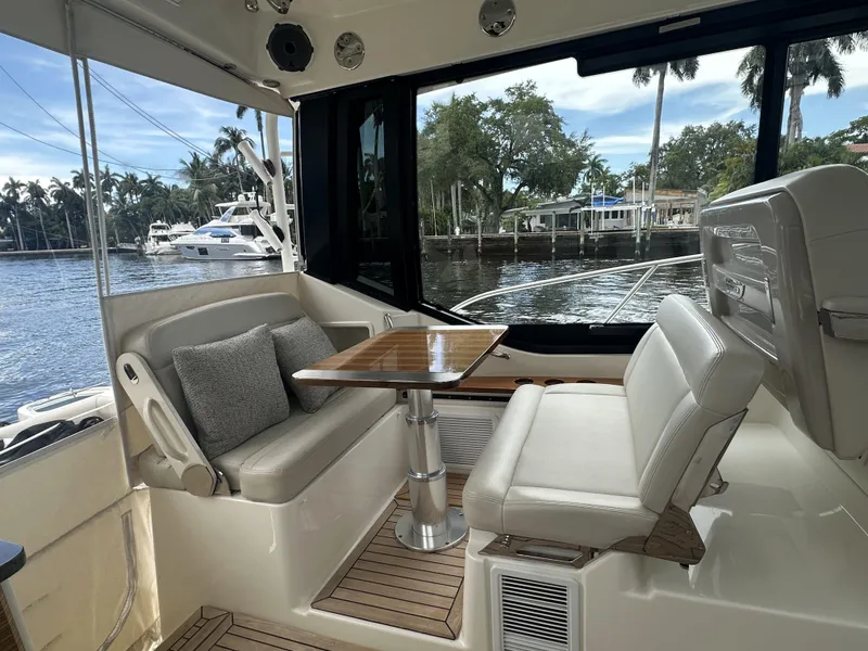 Slide: The Image of 2022 Boston Whaler 405 Conquest interior with seating and table, overlooking marina. - 4