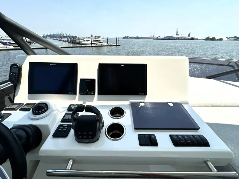 Slide: The Image of Helm of 2022 Prestige 520 yacht with navigation screens and controls, overlooking marina. - 25