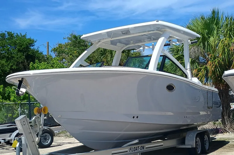 The Image of 2025 Robalo R257 Dual Console boat on trailer, parked outdoors under blue sky. - 0