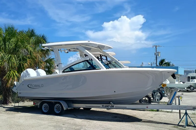 Slide: The Image of 2025 Robalo R257 Dual Console boat on trailer, parked outdoors under blue sky. - 2