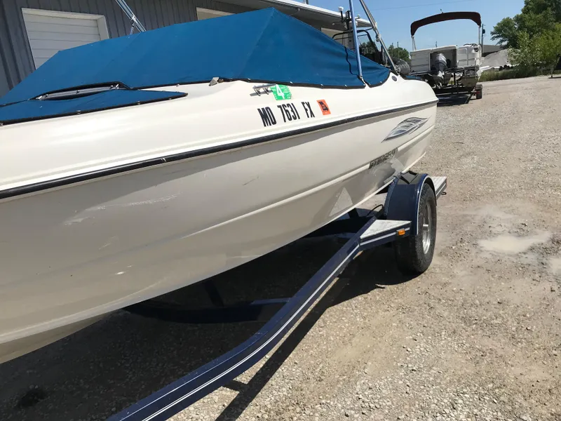 Slide: The Image of 2012 Stingray 195 RX boat on trailer with blue cover, parked outdoors. - 4