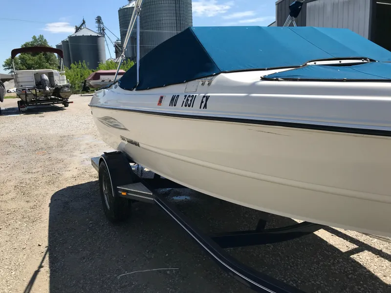 Slide: The Image of 2012 Stingray 195 RX boat with blue cover on trailer, parked outdoors. - 5