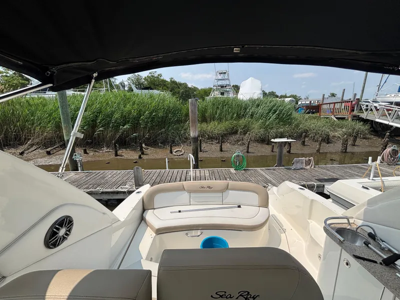 Slide: The Image of 2014 Sea Ray 330 Sundancer docked, featuring spacious seating and lush greenery in the background. - 14