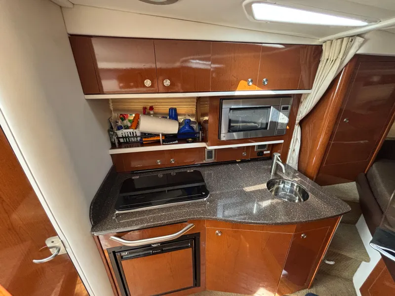 Slide: The Image of 2014 Sea Ray 330 Sundancer yacht kitchen with microwave, sink, and wooden cabinetry. - 20