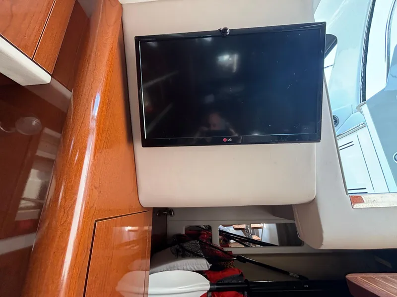 Slide: The Image of Interior of 2014 Sea Ray 330 Sundancer with mounted LG TV and wooden cabinetry. - 26