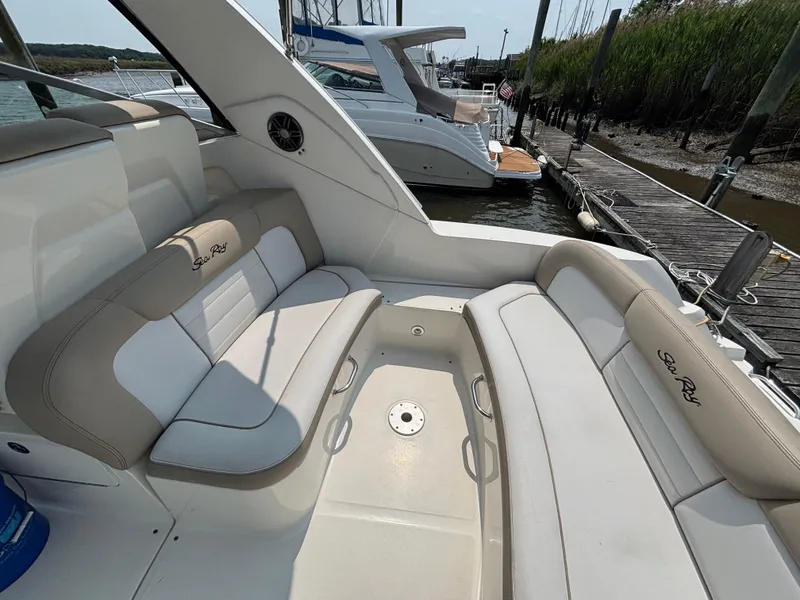 Slide: The Image of 2014 Sea Ray 330 Sundancer boat interior with cushioned seating at a marina. - 8