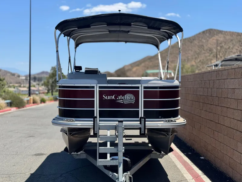Slide: The Image of 2021 SunCatcher Select 18C pontoon boat on trailer, parked near a brick wall. - 3