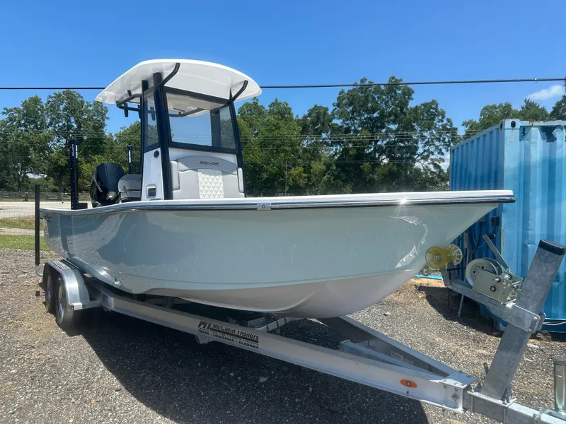 The Image of 2026 Action Craft 24 Bay boat on trailer, parked outdoors under clear blue sky. - 0