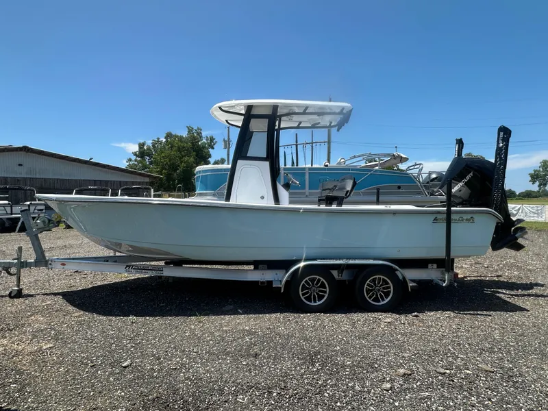 Slide: The Image of 2026 Action Craft 24 Bay boat on trailer, parked outdoors under clear blue sky. - 2