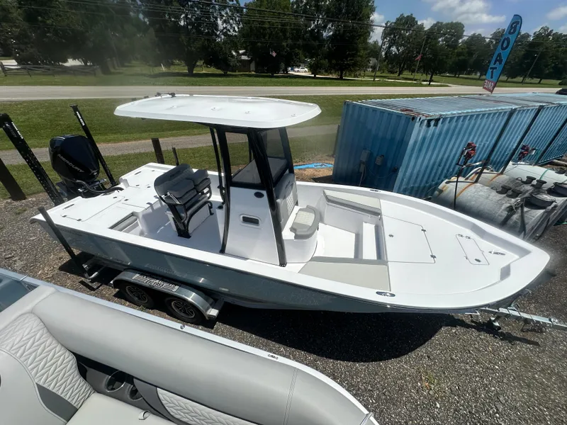 Slide: The Image of 2026 Action Craft 24 Bay boat on trailer, parked outdoors, with T-top and seating. - 13