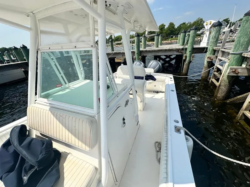 Slide: The Image of 2005 Regulator 26 Forward Seating boat docked at a marina, featuring spacious deck and seating. - 11