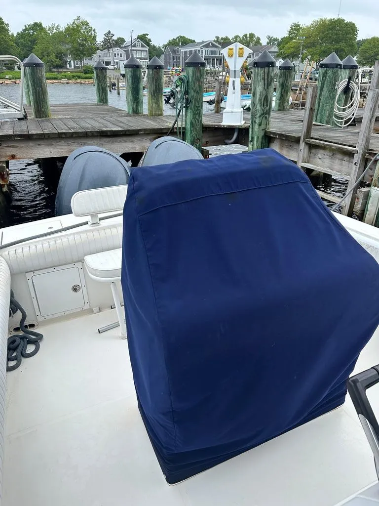 Slide: The Image of 2005 Regulator 26 Forward Seating boat with blue cover, docked at a marina. - 3