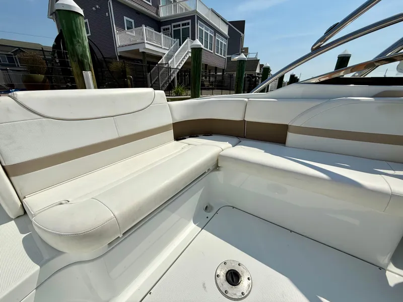 Slide: The Image of 2011 Formula 270 Bowrider boat interior with white and beige seating, docked near waterfront homes. - 10