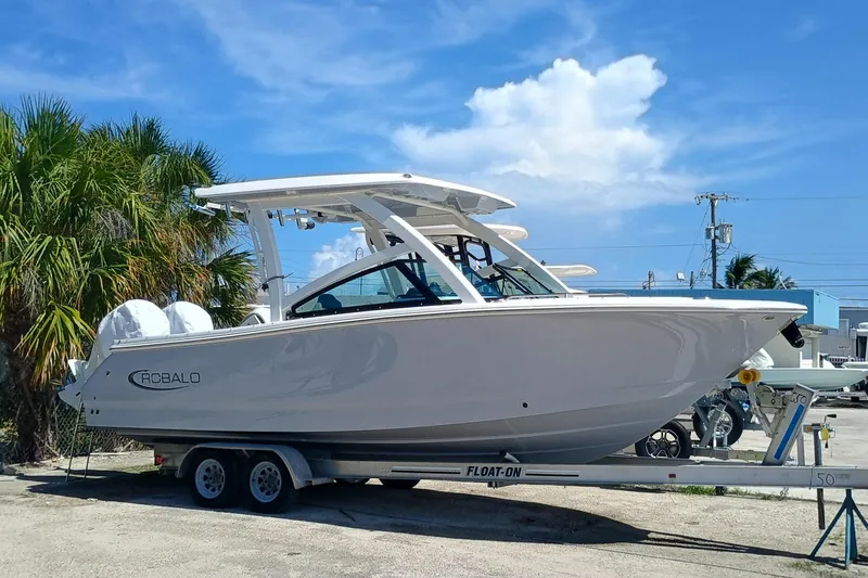 The Image of 2025 Robalo R257 Dual Console boat on trailer, parked outdoors under blue sky. - 0