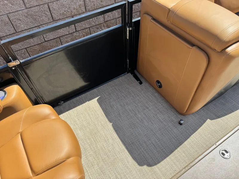 Slide: The Image of 2021 Regency 230 LE3 boat interior with tan leather seats and carpeted flooring. - 15