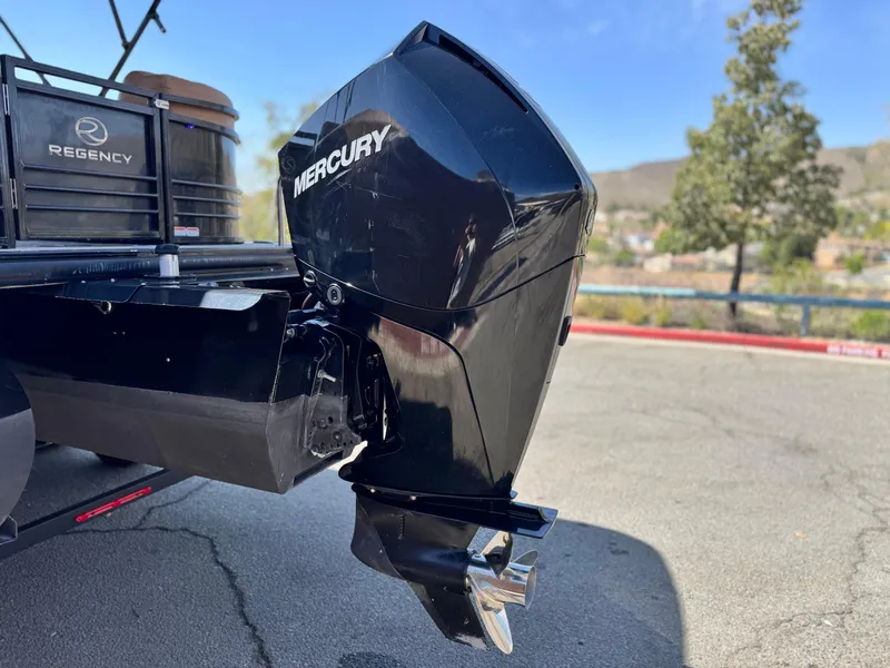 Slide: The Image of 2021 Regency 230 LE3 boat with Mercury outboard motor, parked outdoors. - 6