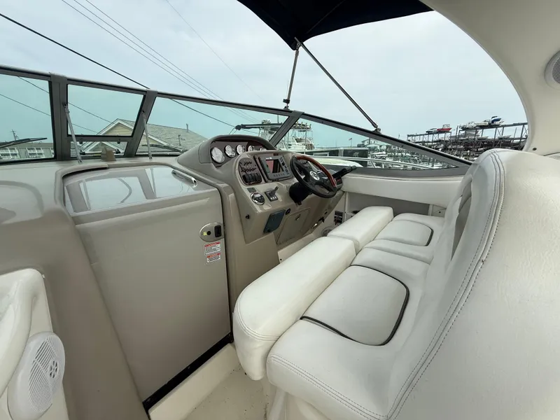 Slide: The Image of 2006 Sea Ray 300 Sundancer helm with white seating and modern dashboard. - 13