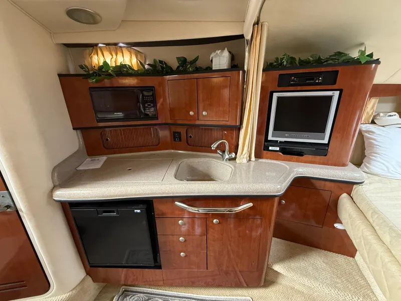 Slide: The Image of Interior of 2006 Sea Ray 300 Sundancer with kitchenette, TV, and wood cabinetry. - 21