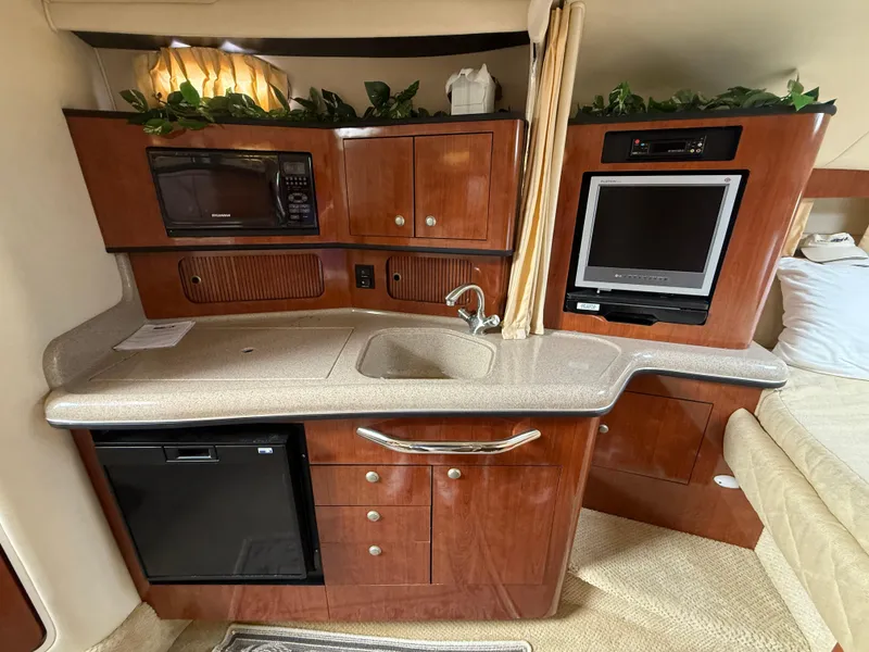 Slide: The Image of 2006 Sea Ray 300 Sundancer interior with kitchenette, microwave, sink, and TV. - 22