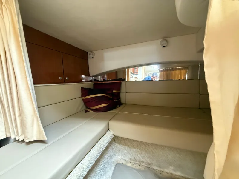 Slide: The Image of Interior cabin of 2006 Sea Ray 300 Sundancer with beige seating and striped pillows. - 24