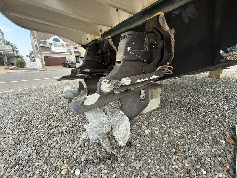 Slide: The Image of 2006 Sea Ray 300 Sundancer boat propellers on gravel, showcasing dual outdrive system. - 46