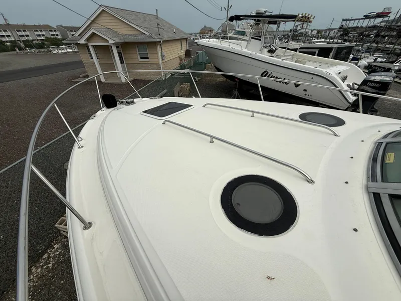 Slide: The Image of 2006 Sea Ray 300 Sundancer boat on land, showcasing deck and railing. - 5