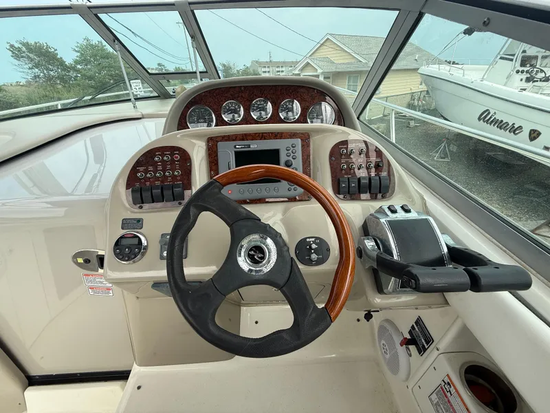 Slide: The Image of 2006 Sea Ray 300 Sundancer helm with wood-accented steering wheel and control panel. - 7