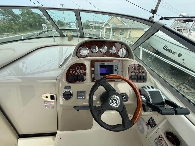Slide: The Image of 2006 Sea Ray 300 Sundancer helm with gauges, steering wheel, and navigation controls. - 8