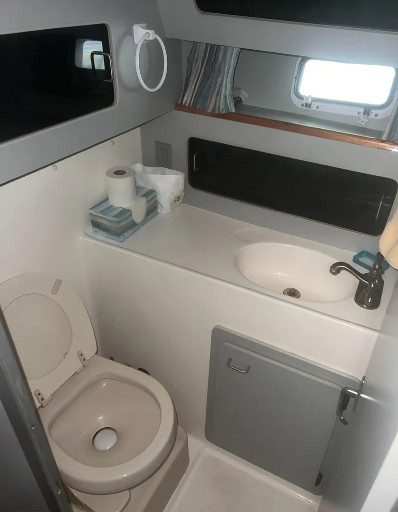 Slide: The Image of 1990 Luhrs 3400 Motor Yacht bathroom with toilet, sink, and storage cabinet. - 25