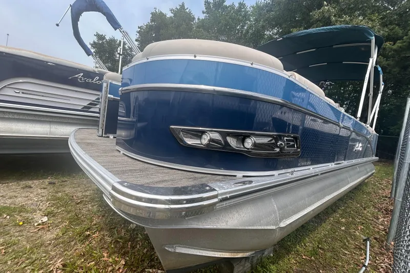 The Image of 2023 Avalon 2585 pontoon boat with blue exterior, docked on grass. - 1