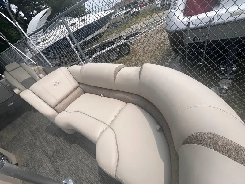 Slide: The Image of 2023 Avalon 2585 boat with beige seating, parked near a chain-link fence. - 10