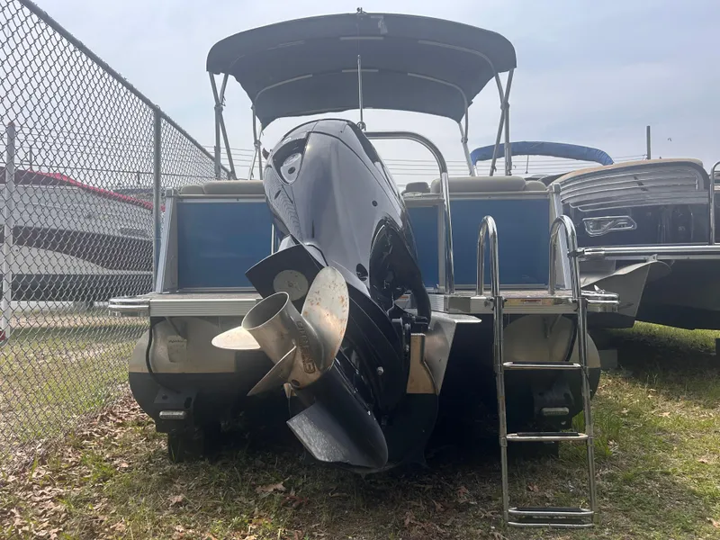 Slide: The Image of 2023 Avalon 2585 pontoon boat with outboard motor and ladder, parked near a chain-link fence. - 11