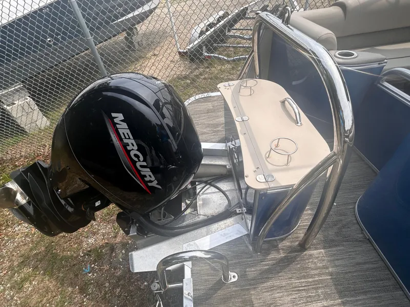 Slide: The Image of 2023 Avalon 2585 boat with Mercury outboard motor, docked near a fence. - 13