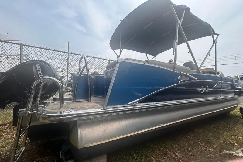 Slide: The Image of 2023 Avalon 2585 pontoon boat with blue exterior and canopy, parked near a fence. - 19