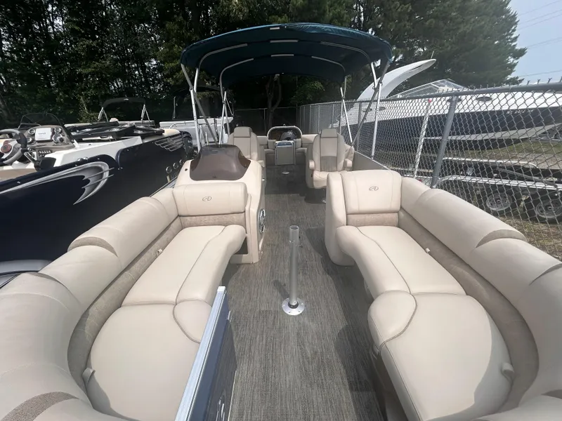 Slide: The Image of 2023 Avalon 2585 pontoon boat with beige seating and canopy, docked near a fence. - 4