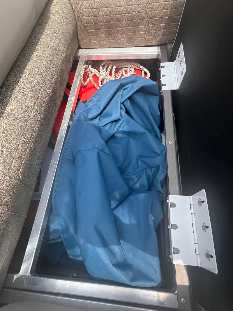 Slide: The Image of Storage compartment in 2023 Avalon 2585 boat with blue tarp and rope. - 6
