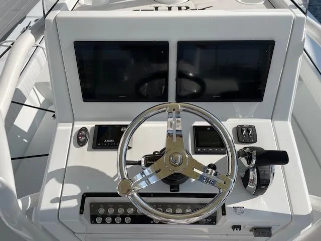 Slide: The Image of 2018 Hell's Bay Estero 24 boat dashboard with dual screens and steering wheel. - 4