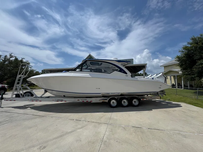 The Image of 2026 Fountain 39 DX boat on trailer, parked outdoors under a partly cloudy sky. - 1