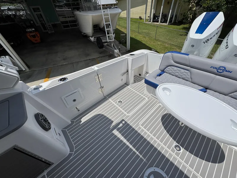 Slide: The Image of 2026 Fountain 39 DX boat deck with seating, table, and outboard motors in a sunny setting. - 38