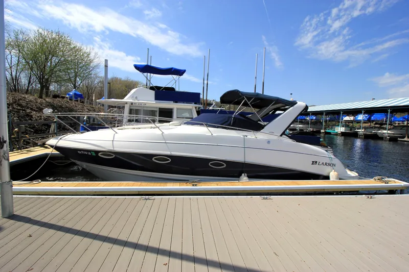 The Image of 2005 Larson Cabrio 310 boat docked at marina under clear blue sky. - 0