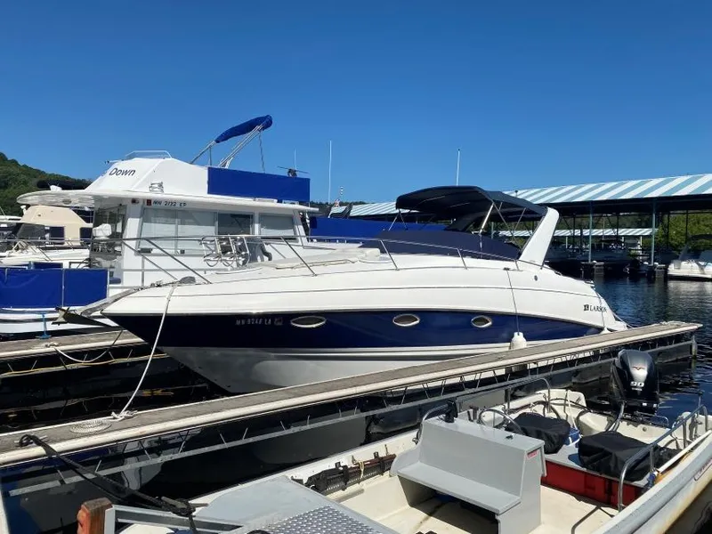 The Image of 2005 Larson Cabrio 310 boat docked at marina under clear blue sky. - 1