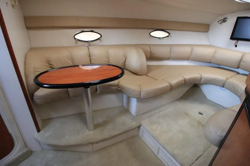 Slide: The Image of Interior of 2005 Larson Cabrio 310 boat with beige leather seating and wooden table. - 12