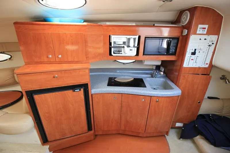 Slide: The Image of 2005 Larson Cabrio 310 boat interior kitchen with wood cabinets, microwave, and sink. - 13