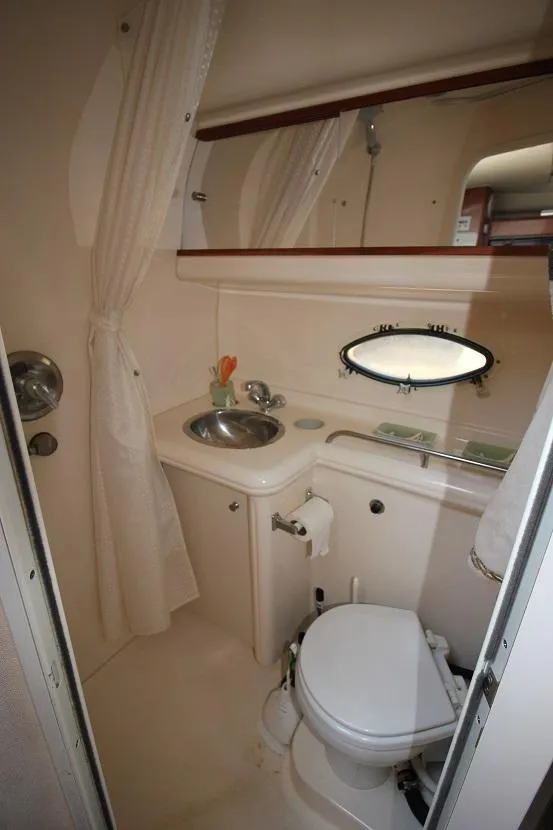 Slide: The Image of 2005 Larson Cabrio 310 boat bathroom with sink, toilet, and porthole window. - 17