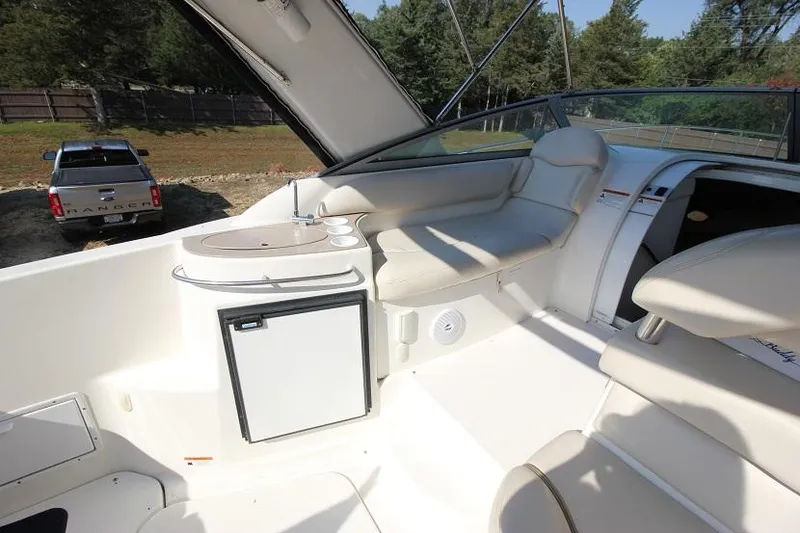 Slide: The Image of 2005 Larson Cabrio 310 boat interior with seating, mini fridge, and outdoor view. - 5