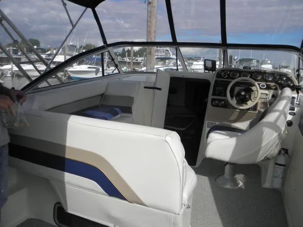 Slide: The Image of 1999 Rinker 280 Fiesta Vee boat interior with helm, seating, and dashboard at marina. - 4