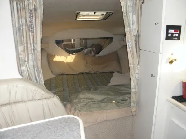 Slide: The Image of 1999 Rinker 280 Fiesta Vee cabin interior with bed, curtains, and storage cabinets. - 5
