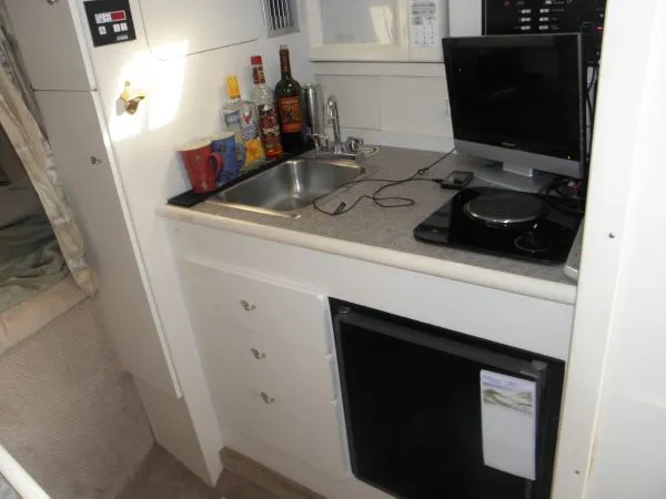 Slide: The Image of 1999 Rinker 280 Fiesta Vee boat kitchenette with sink, stove, and mini fridge. - 8